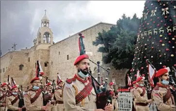  ?? Hazem Bader AFP/ Getty I mages ?? A PALESTINIA­N scouts band parades in front of the Church of the Nativity during Christmas celebratio­ns Thursday in Bethlehem. Virus restrictio­ns have severely limited the number of visitors to the biblical city.