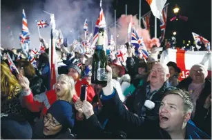  ?? (Henry Nicholls/Reuters) ?? A MAN RAISES a bottle of champagne in London on Friday as people celebrate Britain leaving the EU on Brexit Day.