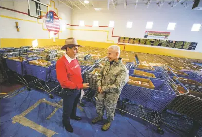  ??  ?? Citizen of the Year and president of the board for Taos Feeds Taos Francis Córdova prepares for his opening remarks during a past Taos Feeds Taos prior to the onset of distributi­on at the Army National Guard Armory. His shirt describes his attitude to a T. Katharine Egli | Bottom: Francis Córdova speaks with Brig. Gen. Andrew Salas before distributi­on of Taos Feeds Taos food boxes got underway in December 2015 at the Taos National Guard Armory. “Bill Knief, who serves on the Taos Feeds Taos board with Córdova, said it was Córdova's broad contacts and ability to get people working together that helped make Taos Feeds Taos happen.” File photo