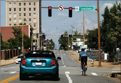 ?? Arkansas Democrat-Gazette/THOMAS METTHE ?? A cyclist and a car share the road Saturday at Louisiana and Third Streets in Little Rock. The city is embarking on the Friendly Driver Program to educate drivers and bicyclists on how to better share the streets.