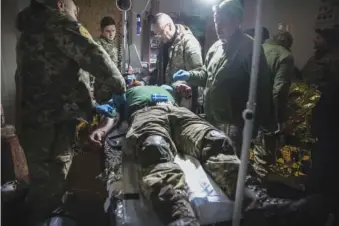  ?? AP PHOTO/YEVHEN TITOV ?? On Monday, medics give first aid to a wounded Ukrainian soldier near Bakhmut, the site of the heaviest battles with Russian troops, in the Donetsk region of Ukraine.