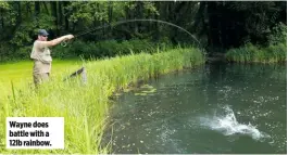  ??  ?? Wayne does battle with a 12lb rainbow.