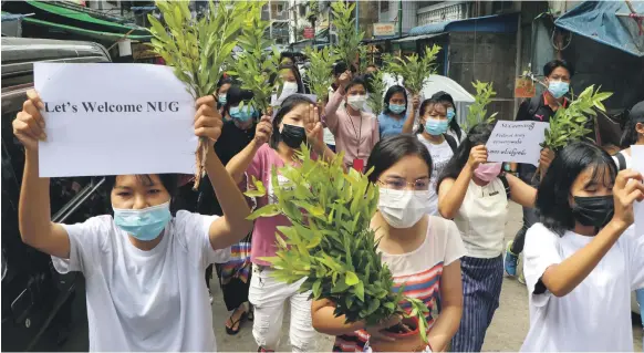  ?? AP ?? Opponents of the military coup in Myanmar at a march in Yangon yesterday carry plants to welcome the newly created NUG, or national unity government