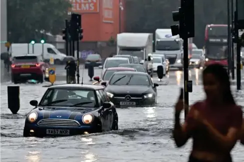  ?? (AFP/Getty) ?? Drivers negotiate flooded roads in southwest London last week