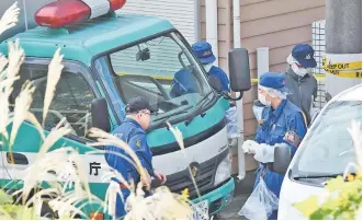  ??  ?? Policemen gather in front of an apartment where Japanese police found nine bodies, including two with their heads severed and dumped in a cool box in Zama, Kanagawa prefecture. — Reuters photo
