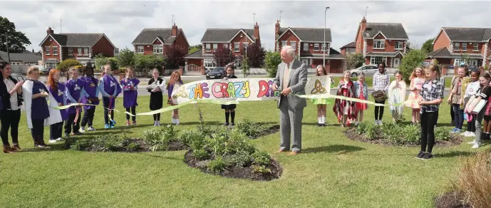  ??  ?? Local man Philip McCabe who is President of the World Beekeeping Federation cutting the ribbon at Presentati­on NS where they have opened a bee friendly garden.