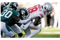  ?? CARLOS OSORIO / ASSOCIATED PRESS ?? Ohio State wide receiver Marvin Harrison Jr. (18) pulls Michigan State cornerback Justin White (30) and cornerback Ameer Speed into the end zone for a touchdown during Saturday’s 49-20 Buckeyes victory.