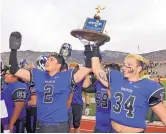  ?? JIM THOMPSON/JOURNAL ?? Manzano players Noah Baca (2) and Cameron Herrera present the Class 6A state trophy to Monarchs fans after a hard-fought victory over La Cueva.