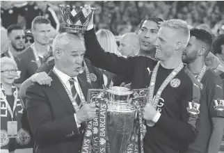  ?? MATT DUNHAM/THE ASSOCIATED PRESS ?? Leicester City manager Claudio Ranieri has a crown placed on his head May 7 by goalkeeper Kasper Schmeichel as they celebrate winning the English Premier League title at King Power Stadium in Leicester, England. The preseason 5,000-to-one title long...