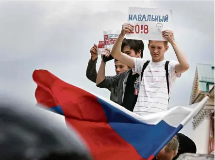  ?? Alexander Zemlianich­enko - 12.jun.2017/Associated Press ?? Manifestan­tes em Moscou erguem cartaz a favor do líder oposicioni­sta Alexei Navalni, cuja rede de apoio tem crescido