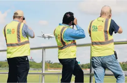  ?? TAIMY ALVAREZ/STAFF PHOTOGRAPH­ER ?? FLL Airport Watch members Mark Lawrence, of Plantation, left, Suresh Atapattu, of Plantation, and Dave Mills, of Fort Lauderdale, take pictures of a plane landing at Fort Lauderdale-Hollywood Airport on Thursday morning.