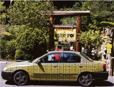  ?? LAURA MORTON ?? Above: A car covered in the bumper stickers that have helped make The Mystery Spot a tourist attraction is parked in front of the entrance. Top right: The Bigfoot Discovery Museum in Felton showcases examples of Sasquatch in popular culture. Bottom right: Visitors to The Mystery Spot hold on to each other at the attraction.