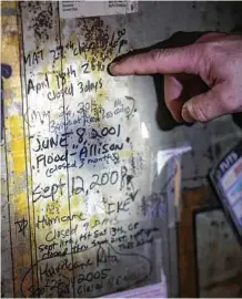  ?? Annie Mulligan ?? Steve Tomlin points to a handwritte­n timeline of flood events on the old safe at the Spaghetti Warehouse.