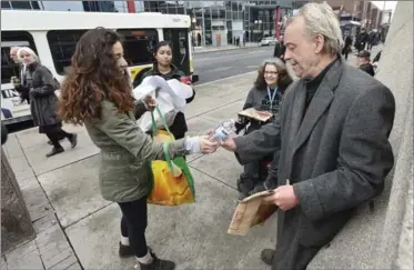  ?? JOHN RENNISON, THE HAMILTON SPECTATOR ?? Daniela Delrazo, 20, hands Edwin Stach a bottle of water as she and Lamisha Khandaker, 20, second from left, wander downtown handing out slices of pizza and bottles of water to the needy. The pair were part of a group of 20 students from McMaster...