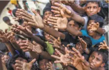  ?? Dar Yasin / Associated Press ?? Rohingya Muslims reach for food at a camp in Bangladesh, where they have taken refuge from violence in Myanmar.