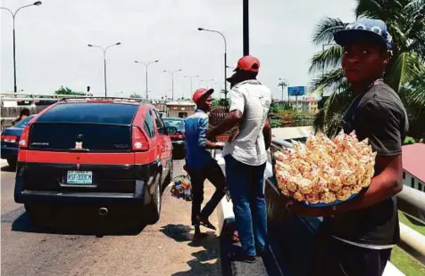  ?? AFP ?? In Nigeria’s financial hub, a noisy, overcrowde­d melting pot of some 20 million people, hawkers can be seen everywhere, snaking between the cars in choking fumes and oppressive heat.