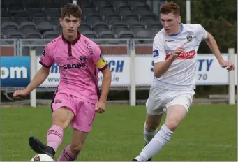  ??  ?? Cian Larkin delivers a pass under pressure from Seán Quinn of U.C.D.