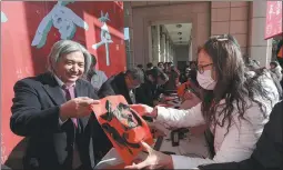  ?? PROVIDED TO CHINA DAILY ?? Middle: Wu Weishan, head of the museum, gives a calligraph­y work of fu (good luck and happiness) to visitors at the museum during Spring Festival.