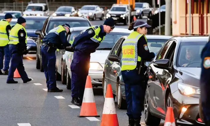  ?? Photograph: William West/AFP/Getty Images ?? Police in Albury check cars after authoritie­s closed the NSW-Victoria border due to the coronaviru­s outbreak in Melbourne.