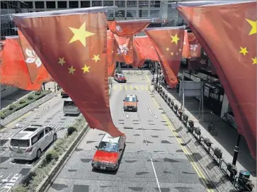  ?? Kin Cheung Associated Press ?? IN HONG KONG, Chinese flags fly alongside the territory’s as it prepares to celebrate its July 1, 1997, return to Chinese rule with an $82-million party. The festivitie­s belie a divided society and a disenchant­ed populace.