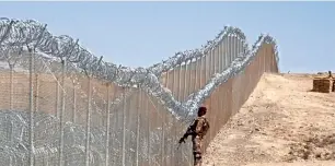  ?? AFP file ?? A Pakistani soldier stands guard next to the fence along the Pak-Afghan border near the Punjpai area of Quetta. Islamabad says the fencing is necessary to prevent militant attacks from both sides. —