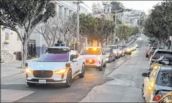  ?? Terry Chea The Associated Press file ?? A Waymo driverless taxi stops on a San Francisco street for several minutes because the back door was not completely shut, as traffic backs up behind it in February 2023.