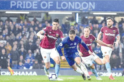  ?? — AFP photo ?? Chelsea's Belgian midfielder Eden Hazard (C) runs past West Ham United's Paraguayan defender Fabián Balbuena (L) and West Ham United's English midfielder Mark Noble (2nd R) during the match at Stamford Bridge.