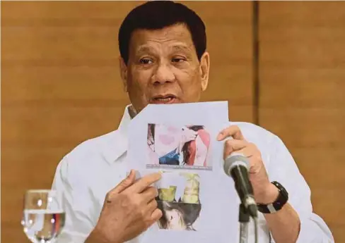  ??  ?? PRESIDEN Filipina, Rodrigo Duterte, menunjukka­n gambar mayat pembantu rumah Filipina yang ditemui dalam peti sejuk di rumah majikannya di Kuwait. - AFP