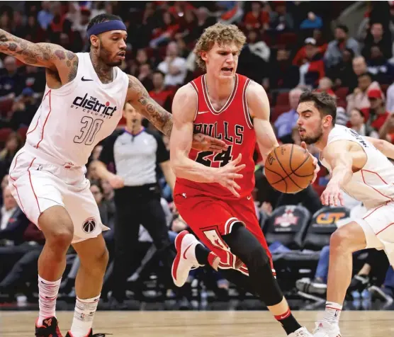  ?? JONATHAN DANIEL/ GETTY IMAGES ?? Lauri Markkanen, splitting Mike Scott ( left) and Tomas Satoransky of theWizards, had a game- high 23 points and made five three- pointers.