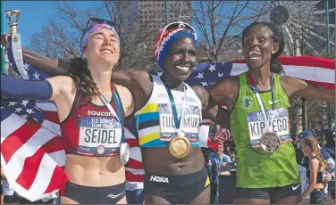  ?? (File Photo/AP/John Amis) ?? First-place finisher Aliphine Tuliamuk (center), second-place finisher Molly Seidel (left) and third-place finisher Sally Kipyego celebrate on the podium after running the women’s U.S. Olympic marathon trials in Atlanta in February 2020. When the Tokyo Summer Games were postponed, U.S. Olympic marathon trials champion Tuliamuk decided with her fiance last year to have a baby instead of waiting.