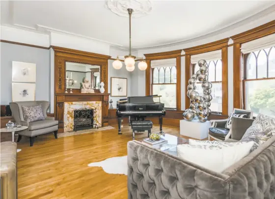  ?? Olga Soboleva/Vanguard Properties ?? The living room of 880 Ashbury St. features a fireplace with marble surround, ceiling medallion and ornate hardwood details.