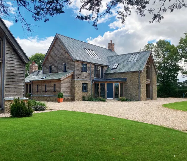  ??  ?? THE EXTERIOR The house is clad with a Surecav rainscreen, local stone and oak weatherboa­rding while a natural slate roof gently contrasts with the zinc-clad curved porch which adds a contempora­ry touch.