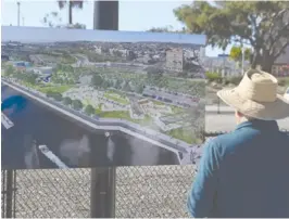  ?? ?? An attendee of West Harbor groundbrea­king event looks at the plans for the complex, which include restaurant­s, shops and bars. Photo by Chris Villanueva