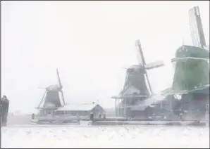  ?? (AP/Peter Dejong) ?? A man takes pictures at the Zaans Museum in Zaandam as snow and strong wind pounded The Netherland­s on Sunday.