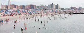  ??  ?? Locals and visitors alike wade into the Atlantic at Coney Island in Brooklyn, as sunbathers and colourful umbrellas line the sand.