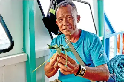  ??  ?? Boat crew Roquero Enrile weaving coconut leaves.