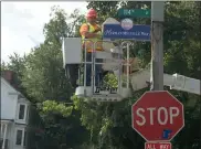  ?? MICHAEL GWIZDALA — MEDIANEWS GROUP ?? A worker hangs the “Hemran Melville Way” sign under the 114th Street sign in Troy.