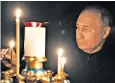  ?? ?? Vladimir Putin lights a candle to commemorat­e the victims in Moscow