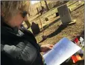  ??  ?? Marcia DePalma looks over a list of settlers buried at the cemetery.