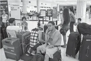  ??  ?? Nathaniel Laboy, center, waits in line Tuesday at the airport in San Juan, Puerto Rico, in hopes of getting a flight to Florida. The scale of destructio­n caused by Hurricane Maria, combined with Puerto Ricans’ legal right to move anywhere in the U.S.,...