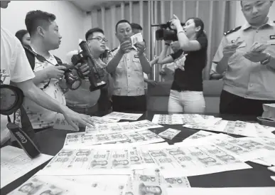  ?? LI ZONGHUA / FOR CHINA DAILY ?? Cash grab
Police officers show counterfei­t renminbi notes that were seized in a recent case in Xi’an, Shaanxi province, on Monday. Two men are in police custody for printing the notes, with face values of 10 and 20 yuan, and selling them online. The...