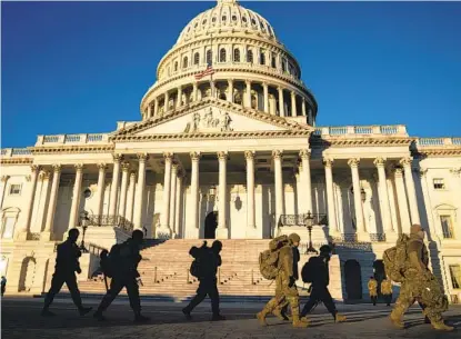  ?? ANNA MONEYMAKER THE NEW YORK TIMES ?? Members of the Army National Guard walk to board a bus after working a shift at the U.S. Capitol on Sunday.