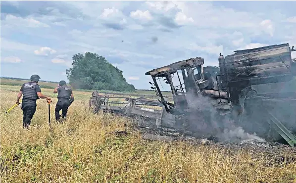  ?? ?? Sappers examine a burnt out harvester that hit an anti-tank mine in a wheat field near the village of Vilkhivka in Kharkiv region at the weekend