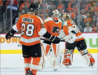 ?? TOM MIHALEK — THE ASSOCIATED PRESS ?? Flyers captain Claude Giroux watches a time-honored tradition unfold Wednesday — the postseason changing of the struggling goalies, with Brian Elliott, center, skating off to be replaced by Michal Neuvirth in the second period of a 5-0 Game 4 loss to...