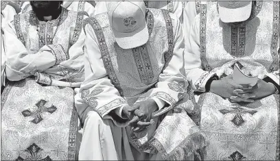  ?? [NARIMAN EL-MOFTY/THE ASSOCIATED PRESS] ?? Priests wearing ballcaps to protect them from the sun lower their heads as they attend a Mass celebrated by Pope Francis for Egypt’s tiny Catholic community. The ceremony Saturday was at the Air Defense Stadium in Cairo.