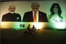  ?? Ajit Solanki/Associated Press ?? Cyclists ride past a giant banner welcoming President Donald Trump on Saturday in Ahmedabad, India.