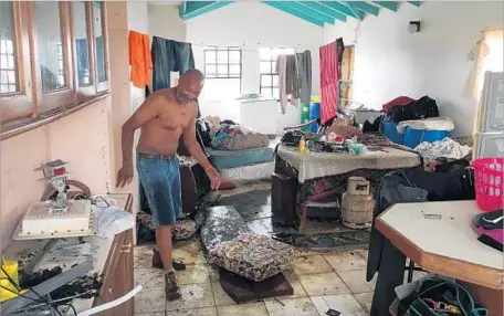  ?? Ann Simmons Los Angeles Times ?? DEVON CHRISTIAN walks through his neighbor’s f looded home on Barbuda. One of his own houses was destroyed by Hurricane Irma.