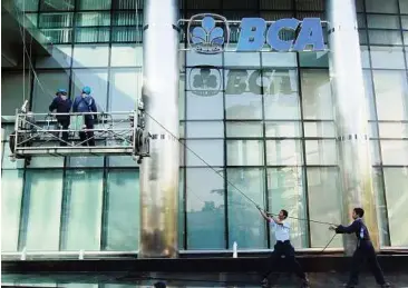  ??  ?? Workers help to pull up a mobile platform outside a bank’s office in Jakarta. As fiscally discipline­d Asian economies have much lower levels of government debt than Western markets, there may not be enough of such assets to go round. — Reuters