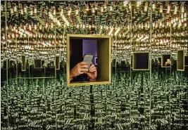  ?? WASHINGTON POST PHOTO BY BILL O’LEARY ?? A visitor pokes her op-art smartphone into the window of “Infinity Mirrored RoomLove Forever” during 2017 press previews for “Yayoi Kusama: Infinite Mirrors” at the Hirshhorn in Washington.