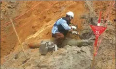  ?? SUPPLIED ?? A CMAC official unearths one of the two unexploded Mk 82 bombs on Sunday in Kandal province.